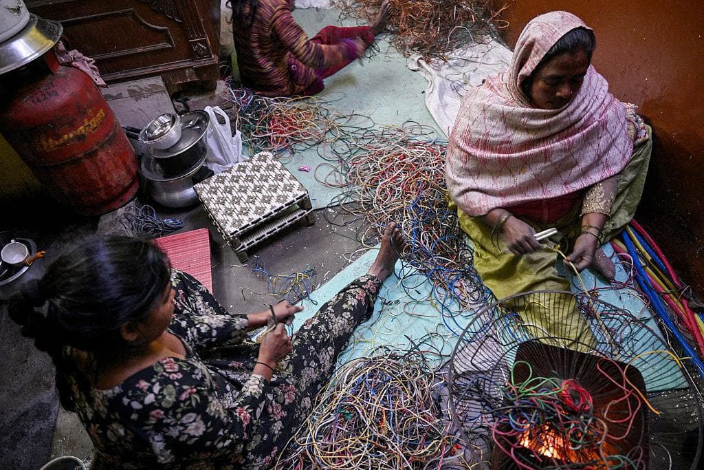 Informal workers stripping electrical wires by hand on the floor